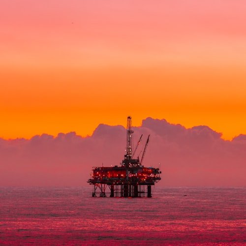 Oil rig at sunset representing oil price surge amid US-Iran conflict